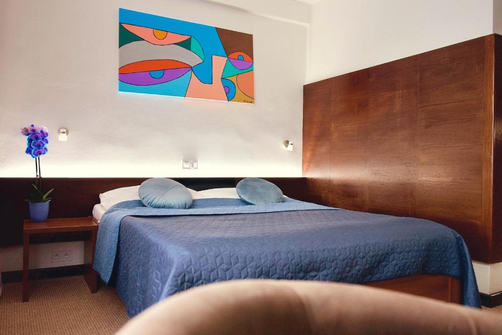 a bedroom with a blue bed and a painting on the wall at Hotel Merkur - Jablonec nad Nisou in Jablonec nad Nisou