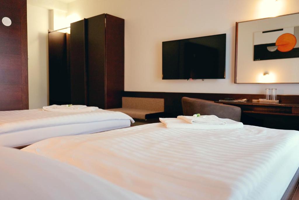 a hotel room with two beds and a flat screen tv at Hotel Merkur - Jablonec nad Nisou in Jablonec nad Nisou