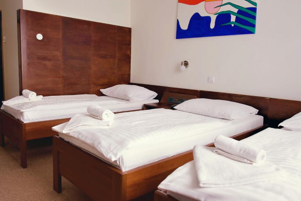 three beds in a room with white sheets at Hotel Merkur - Jablonec nad Nisou in Jablonec nad Nisou