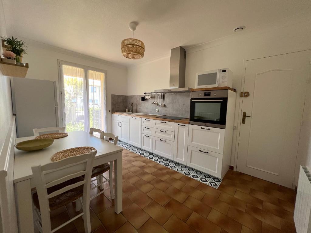 Il comprend une cuisine avec des placards blancs, une table et une télévision. dans l'établissement La Maison d'Orange, à Orange