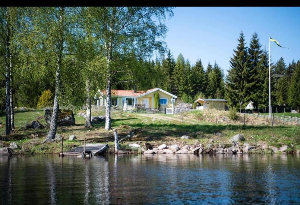 una casa sulla riva di un lago con una barca di Tranquil Lakeside Cottage Retreat i Garpenberg a Garpenberg