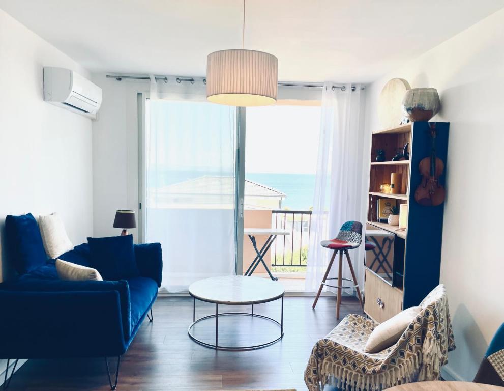a living room with a blue couch and a table at Grand Bleu, Vue sur Lac, Cosy et Chic WIFI Centre ville, Plage in Istres