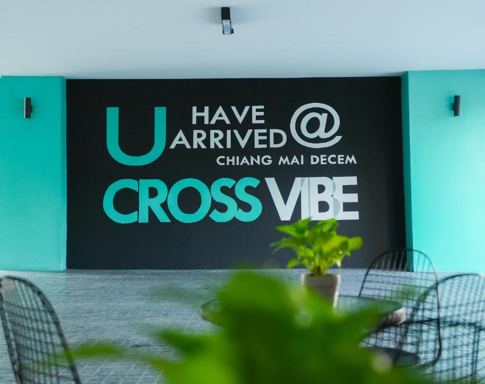 A branded arrival area has a large Cross Vibe Chiang Mai Decem sign and café-style seating.