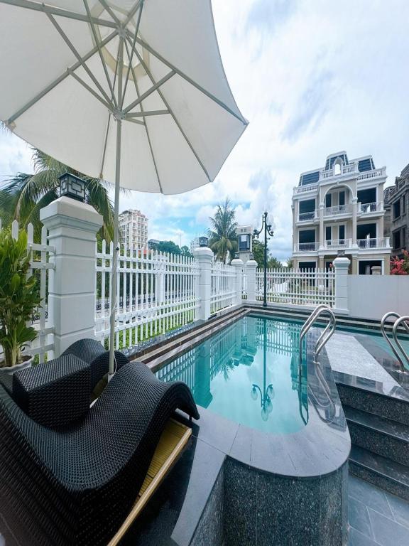 a swimming pool with two chairs and an umbrella at Villa 13 phòng ngủ vip - Đầy đủ tiện nghi - Bể bơi riêng - Bàn Bi a in Ha Long