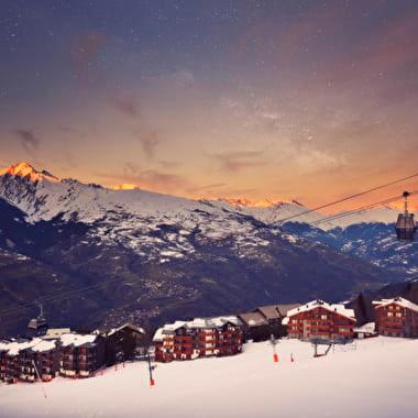 une montagne enneigée avec des maisons et une remontée mécanique dans l'établissement Les Choucas, à Aime La Plagne