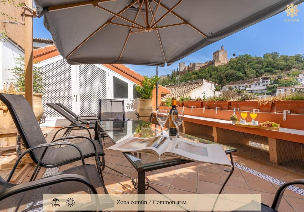 Un patio con una mesa y sillas y una sombrilla. en ADANAR-Apartamentos Muralla Zirí, en Granada
