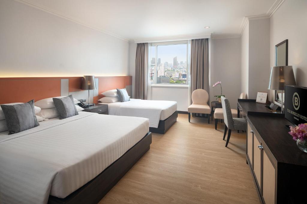 a hotel room with two beds and a television at The Berkeley Hotel Pratunam in Bangkok