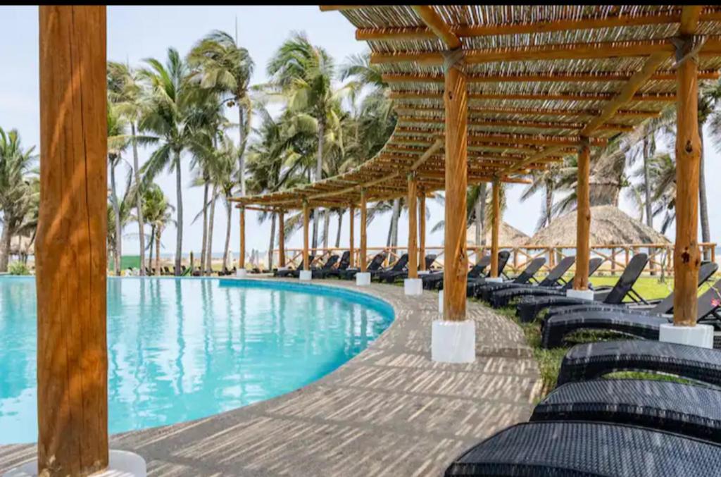 ein Pool in einem Resort mit Stühlen und Palmen in der Unterkunft Casa, alberca, club de playa WI-FI en Acapulco in Barra Vieja