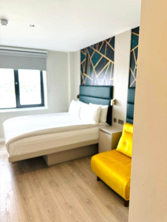 a bedroom with a bed and a yellow chair at Victoria Studios in London