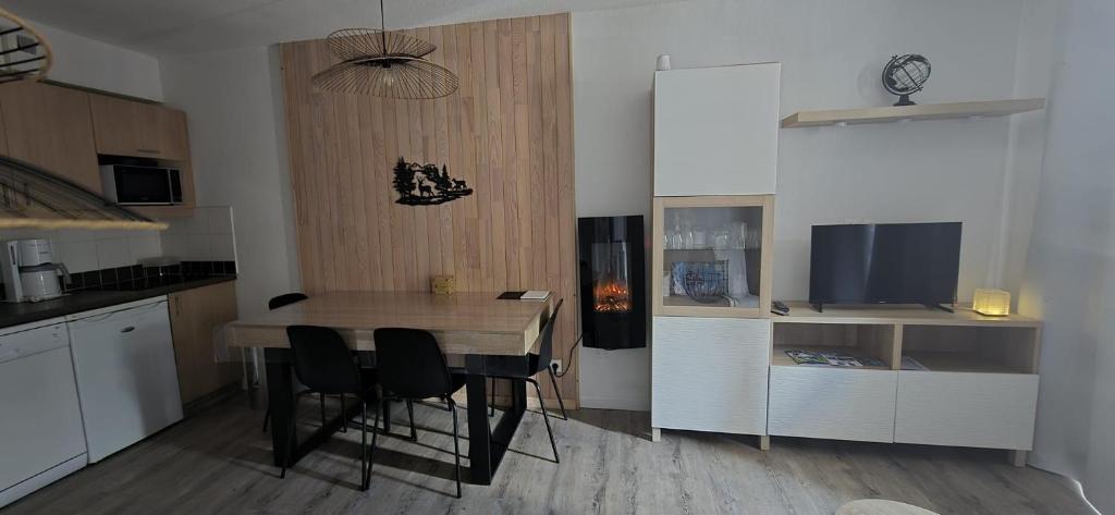 une cuisine avec une table et des chaises ainsi qu'une télévision dans l'établissement Cocon des Orres res balcon des airelles appartement 512, aux Orres