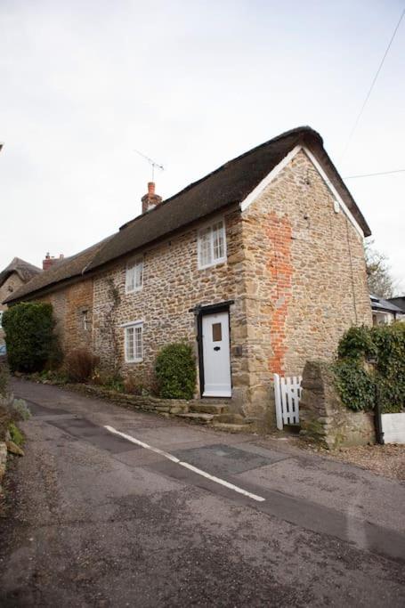 a brick house with a white door on a street at Number 60 Donkey Lane in Burton Bradstock