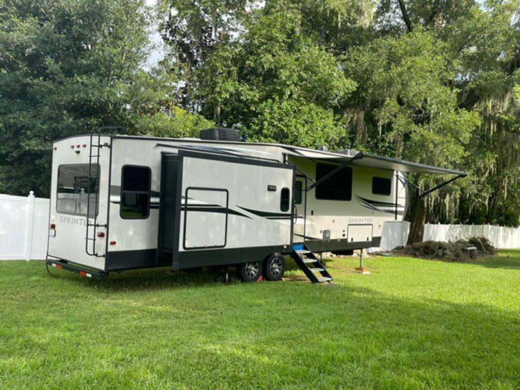 a white trailer parked in a grass field at Downtown Dade City Glamper in Dade City