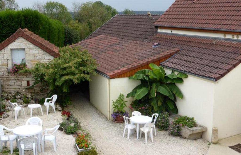 eine Terrasse mit weißen Tischen und Stühlen und ein Gebäude in der Unterkunft Maison d'Hote le Relais de morville in Fresnes