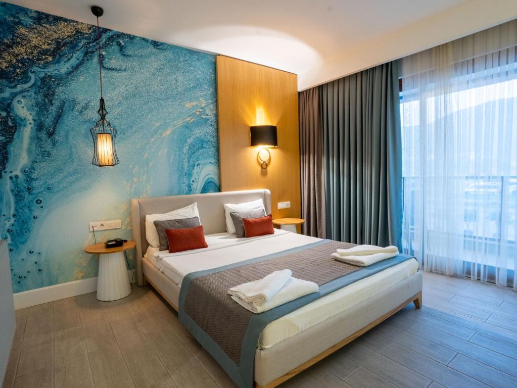 a bedroom with a bed with a large painting on the wall at Calcalar Suit Hotel in Ula