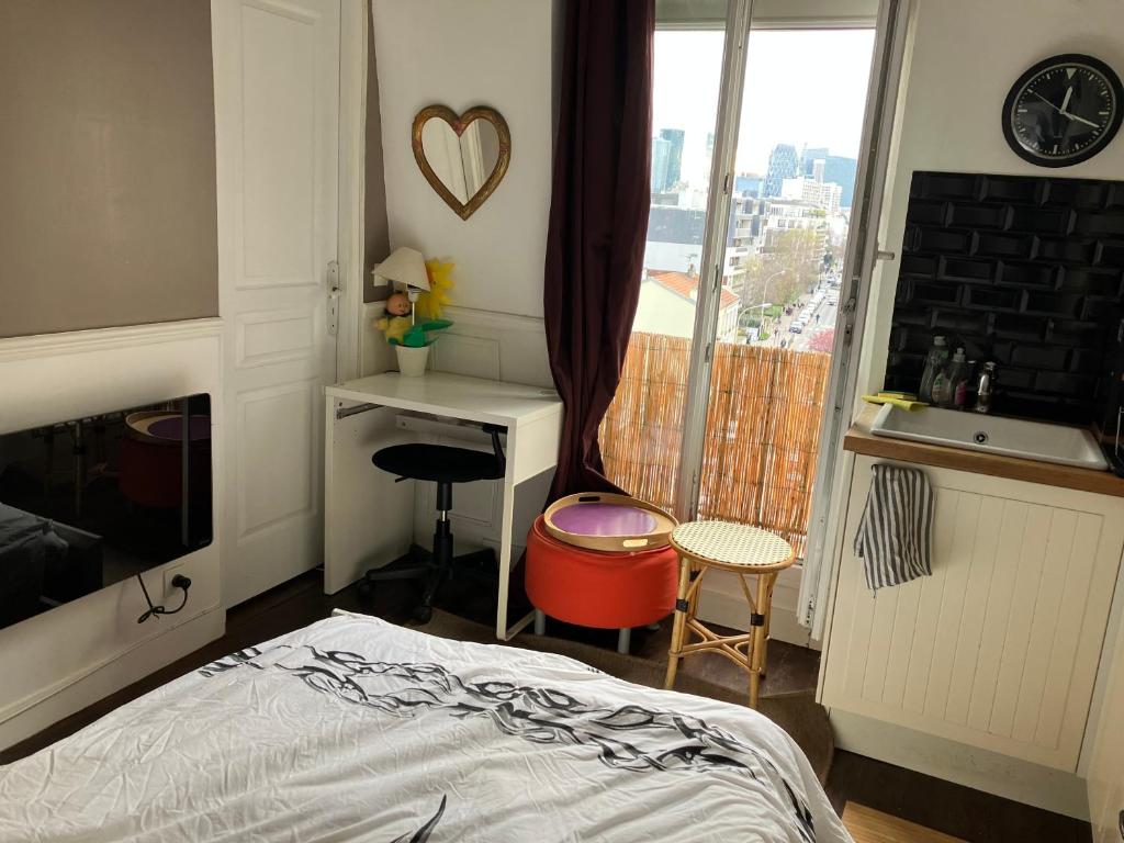 une chambre avec un lit, un bureau et une fenêtre dans l'établissement Furnished studio very quiet with incredible views to La Défense & Eiffel Tower, à Courbevoie