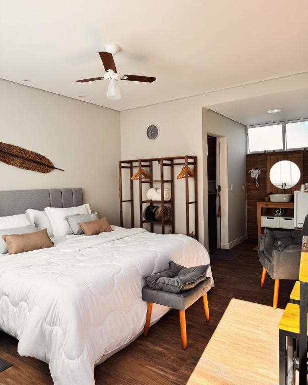 a bedroom with a large white bed with a ceiling fan at La Estância Flats in Iguape