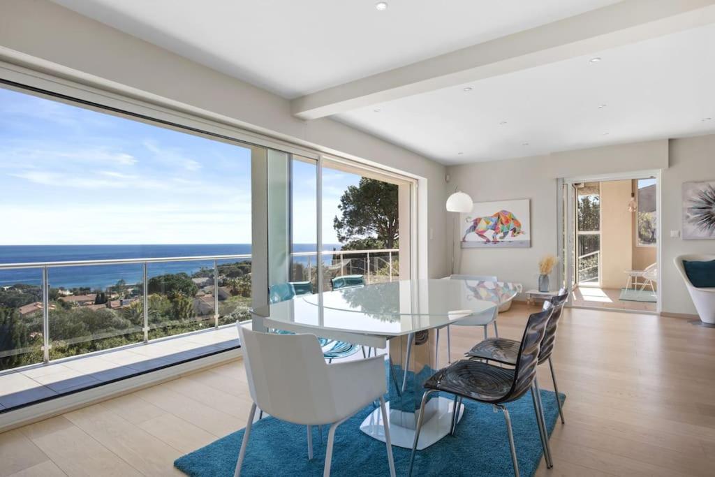une salle à manger avec une table et des chaises et une grande fenêtre dans l'établissement Villa 197 m2, vue mer, parking, à Roquebrune-sur Argens