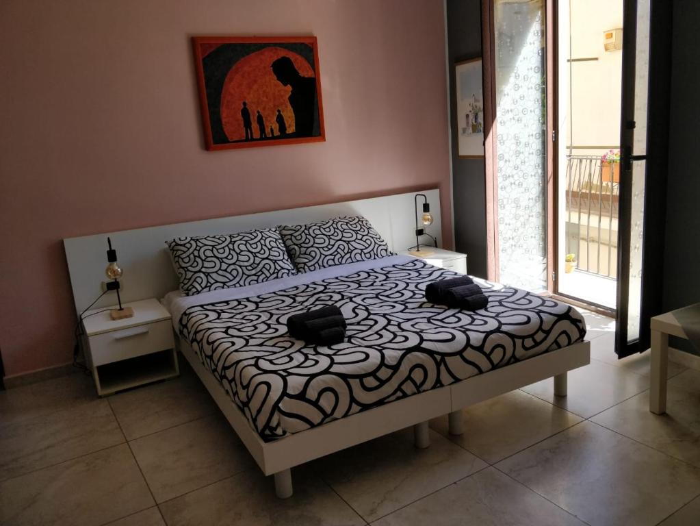 een slaapkamer met een bed met een zwart-wit dekbed bij Kalos Rooms in Agrigento