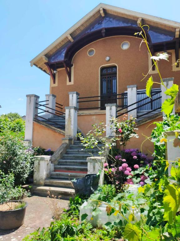 une maison avec des escaliers et des fleurs devant elle dans l'établissement Maison Bonhomme, à Cusset
