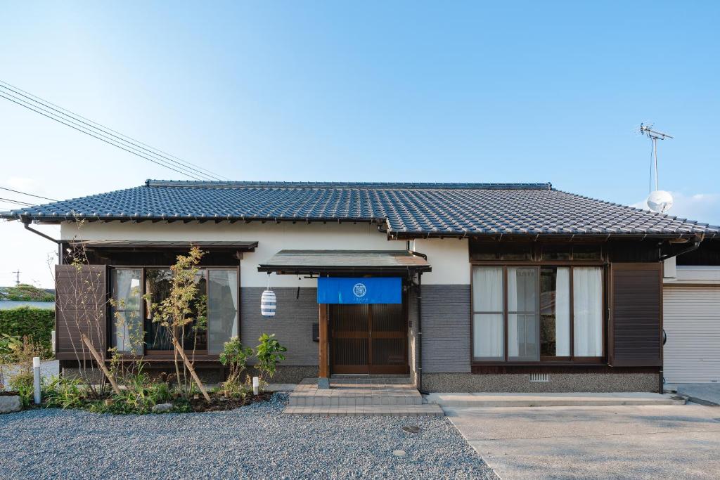 ein Haus mit einem blauen Schild davor in der Unterkunft 一棟貸切の和風プライベートヴィラ プール花火バーベキュー in Fukutsu