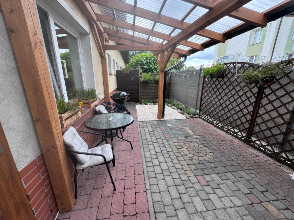 a patio with a pergola and a table and chairs at Apartament na Kanałowej in Sztutowo