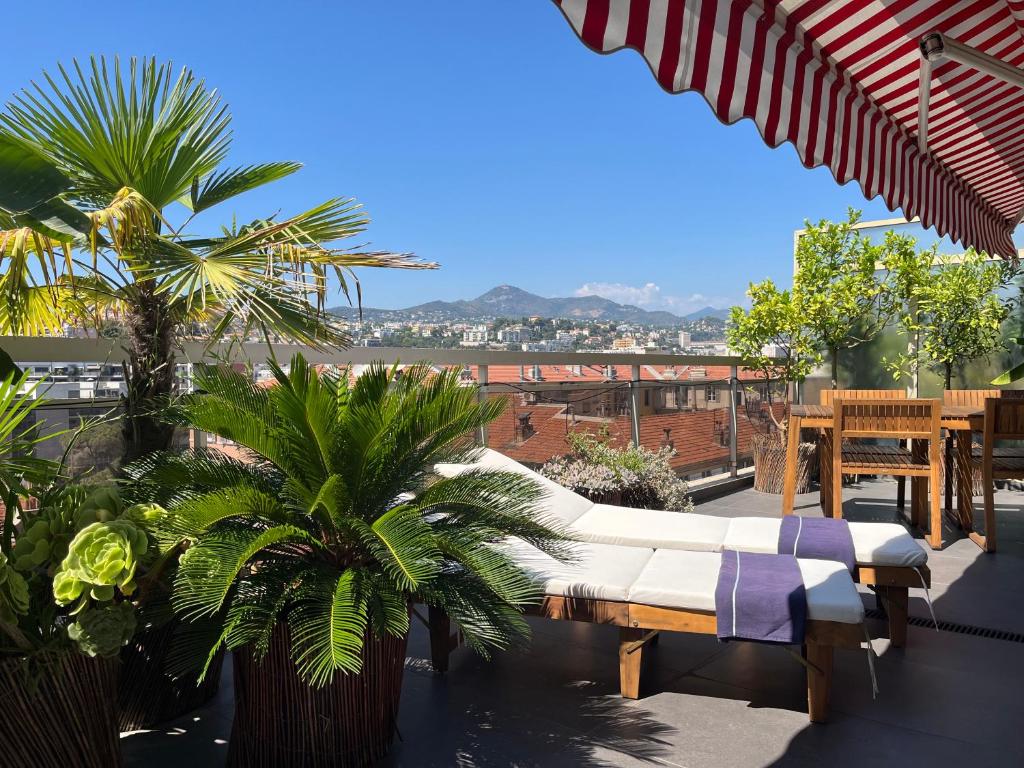 d'une terrasse avec un canapé et des palmiers sur un balcon. dans l'établissement Splendide penthouse au coeur de Nice, à Nice