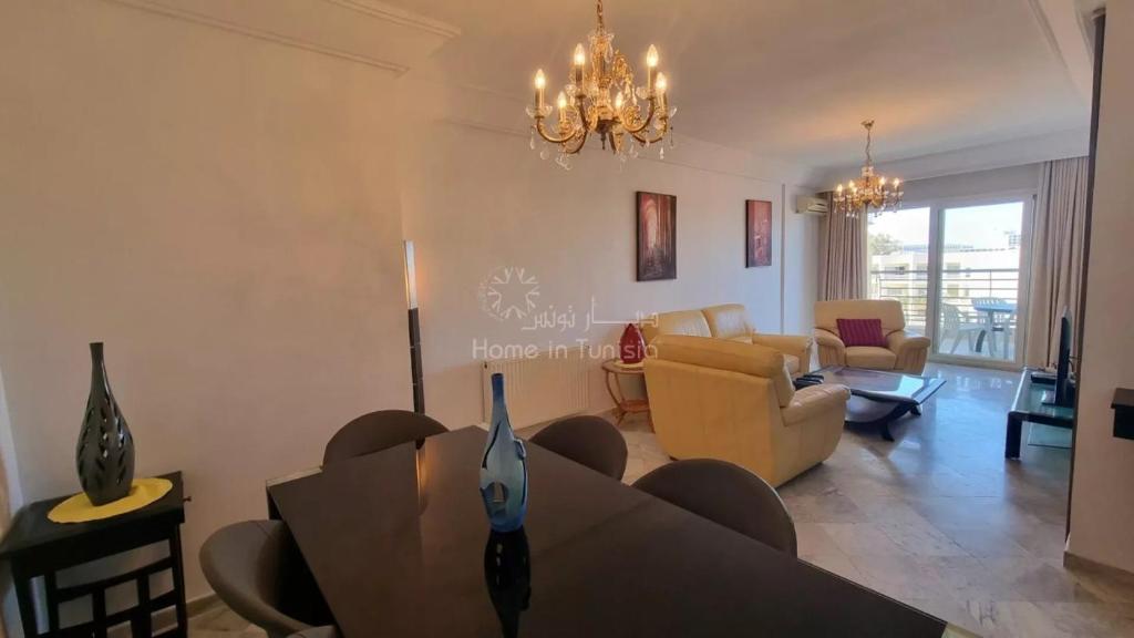 a living room with a couch and a table at Location saisonniere Appartement Sousse Khezama in Kasnadar