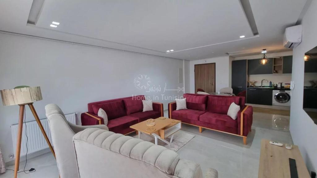 a living room with two red couches and a table at Location saisonniere Appartement Chatt Meriem in Kasnadar