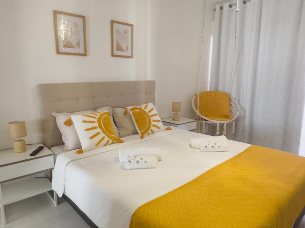 a bedroom with a large bed with yellow and white pillows at Riamar House - Faro City Center in Faro