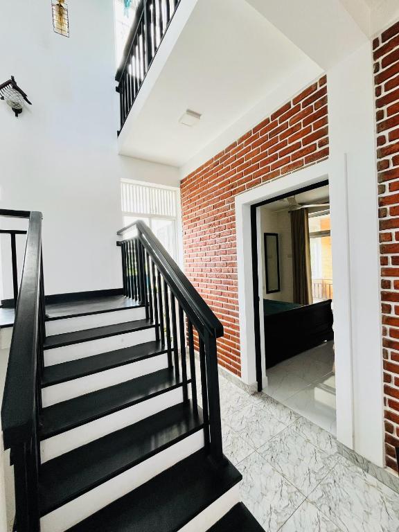 a staircase in a house with a brick wall at Nova's in Piliyandala