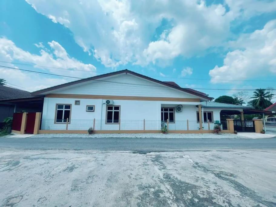 Kota BharuFZ's Paduka Homestay Kubang Kerian的一栋白色的小建筑，背景是多云的天空