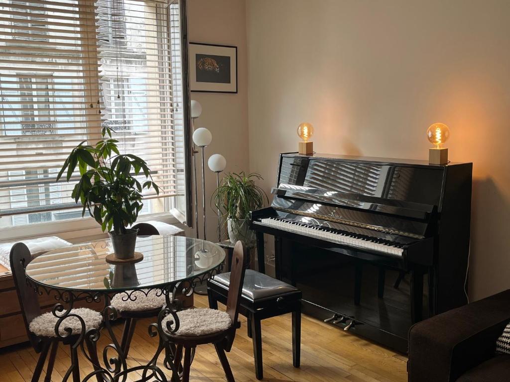 - un salon avec un piano et une table dans l'établissement calme et élégance, à Paris