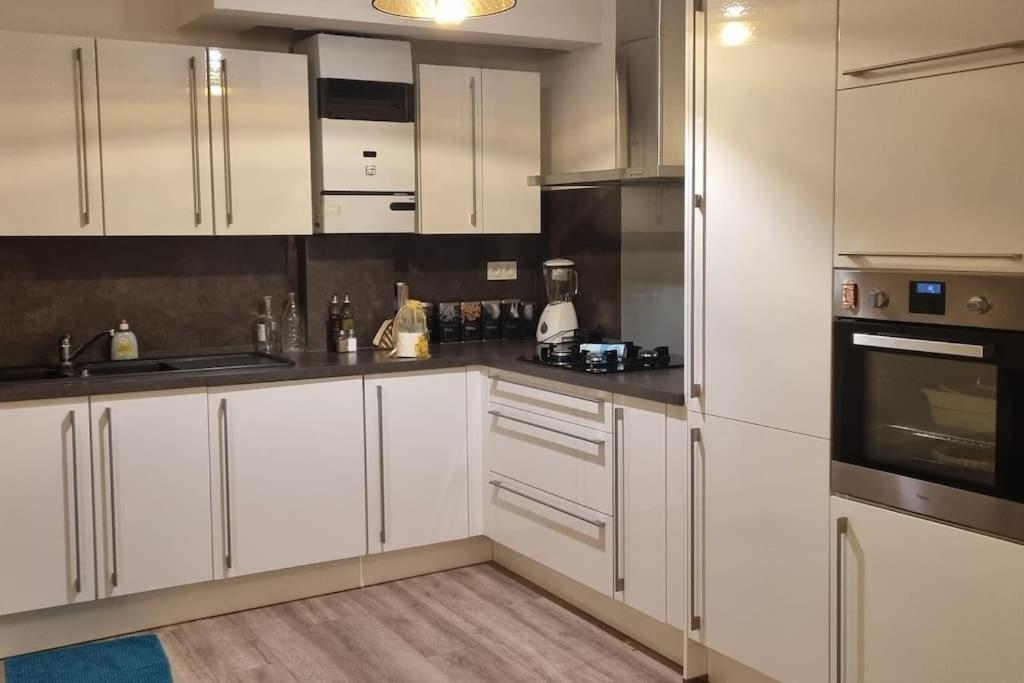 Una cocina con gabinetes blancos y electrodomésticos de acero inoxidable. en Spacieux en plein centre, en Sète