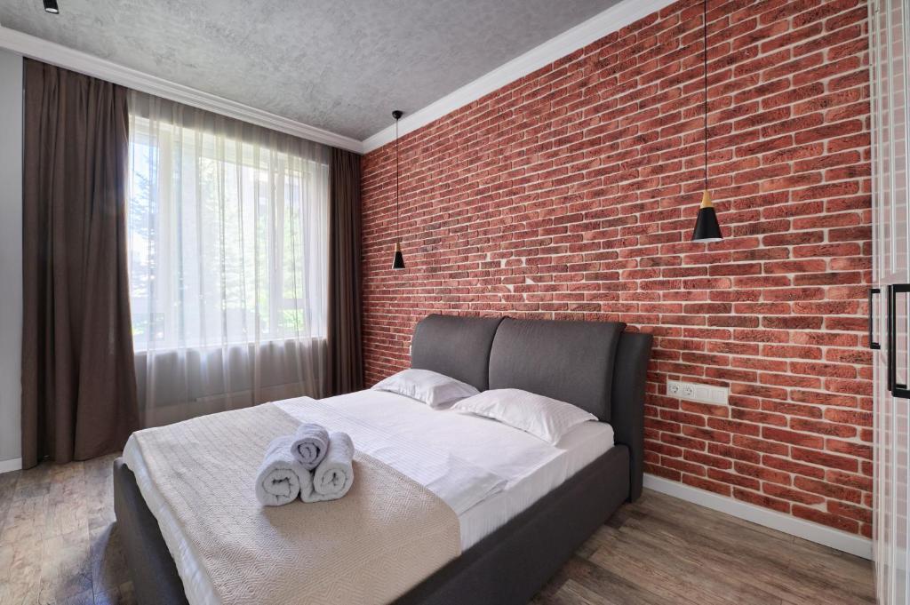 ein Schlafzimmer mit einer Ziegelwand und einem Bett mit Handtüchern in der Unterkunft Роскошные Двухкомнатные Апартаменты in Almaty