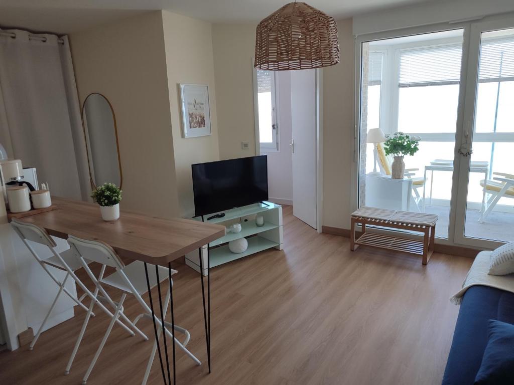 a living room with a table and a television at Vue Panoramique FACE MER in Bray-Dunes