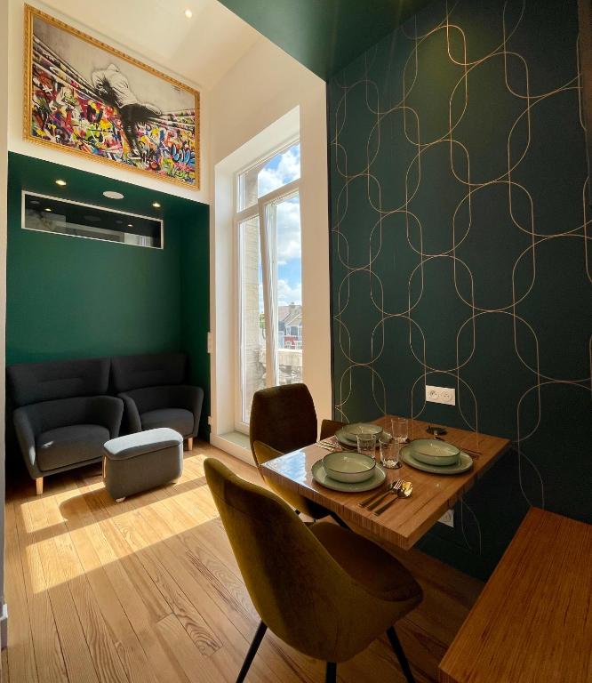 une salle à manger avec des murs verts, une table et des chaises dans l'établissement Le Five - Villa la Potinière - Front de mer, à Dunkerque