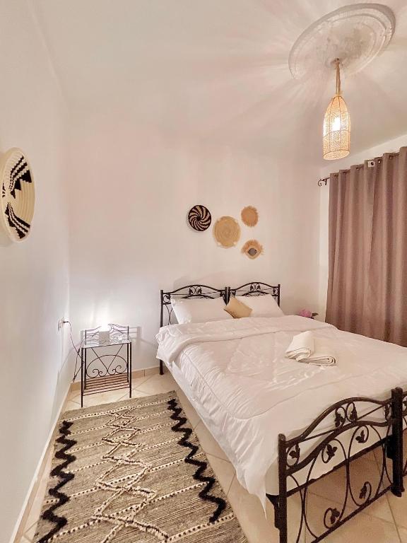 a bedroom with a bed with white sheets and a rug at Dar Bakkali Nadi in Tangier
