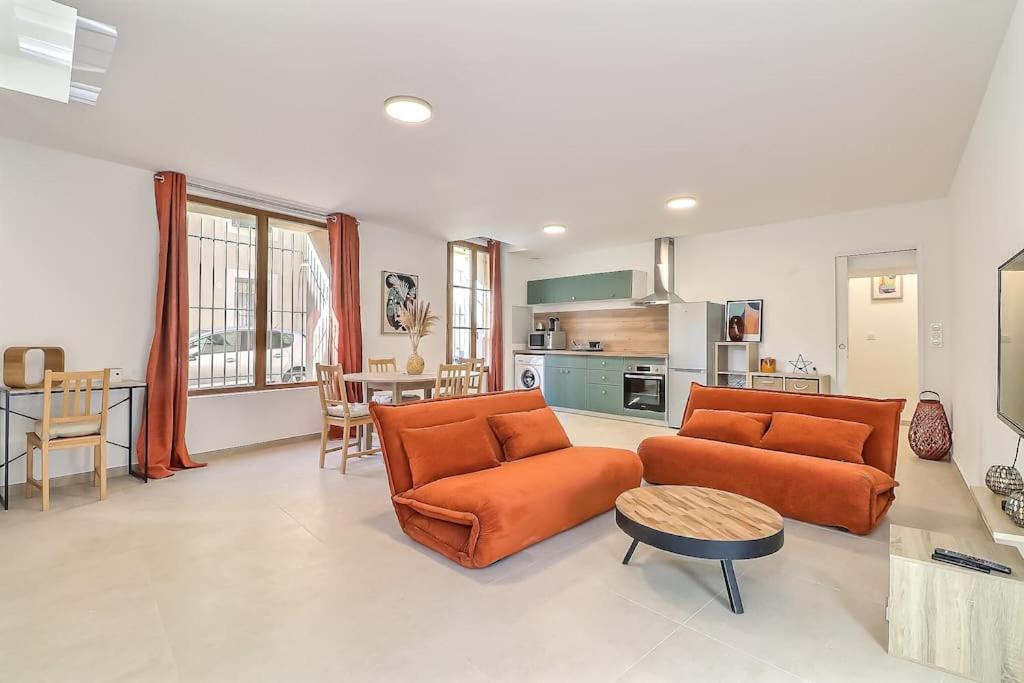 un salon avec deux canapés orange et une cuisine dans l'établissement Appart de 70m2 en RDC à 6 mn à pied des monuments, à Nîmes