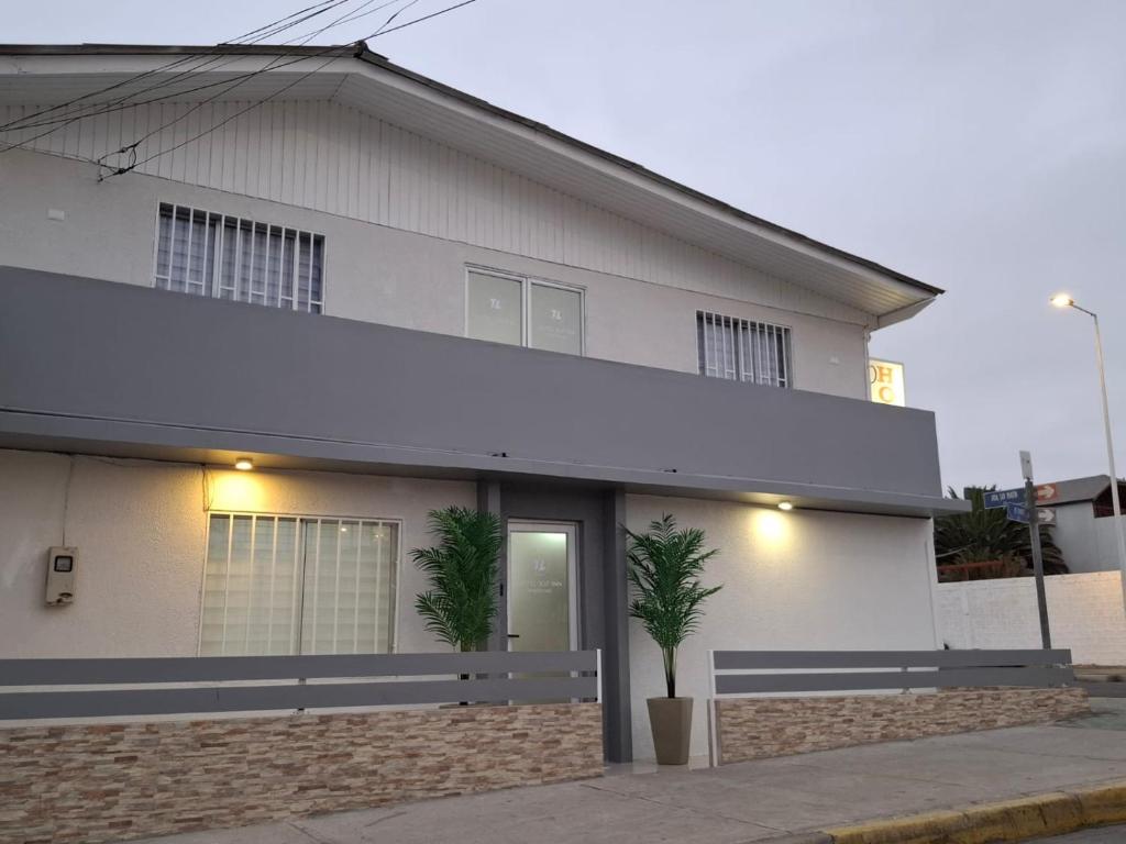 een wit huis met twee palmbomen ervoor bij HOTEL 507 INN in Mejillones