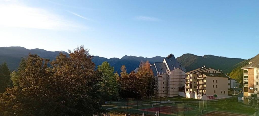 un grupo de edificios y árboles con montañas en el fondo en Ax 3 domaines, en Ax-les-Thermes