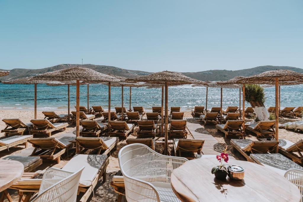 a beach with chairs and tables and umbrellas at Coralli Seaside Resort in Livadakia