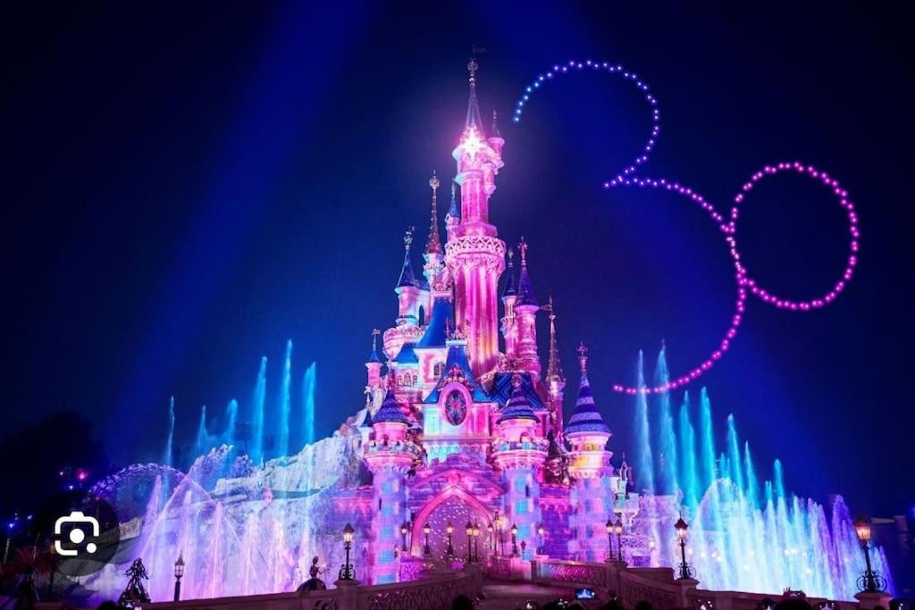 un château de disney est allumé la nuit dans l'établissement Charmant Duplex F2 Disneyland Paris, à Torcy