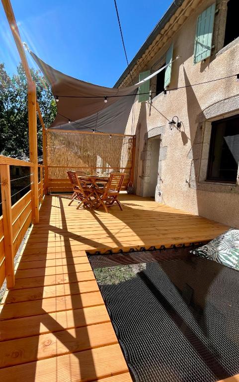 une terrasse en bois avec une table et des chaises dessus dans l'établissement Parenthèse en forêt - Lodge CANOPEE, à Le Bez