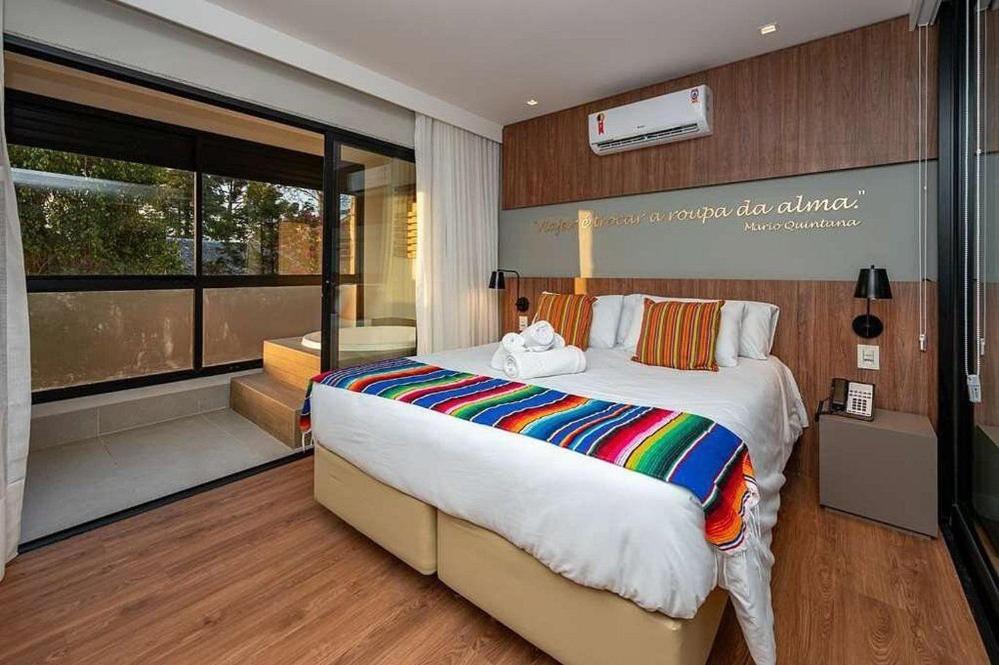 Apartamento sofisticado Campos do Jordão في كامبوس دو جورداو: غرفة نوم بسرير كبير ونافذة كبيرة