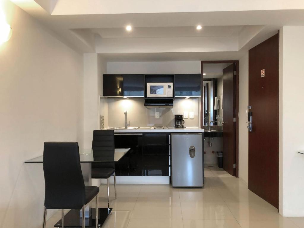 A bright suite interior with a compact black kitchenette and a small dining table.