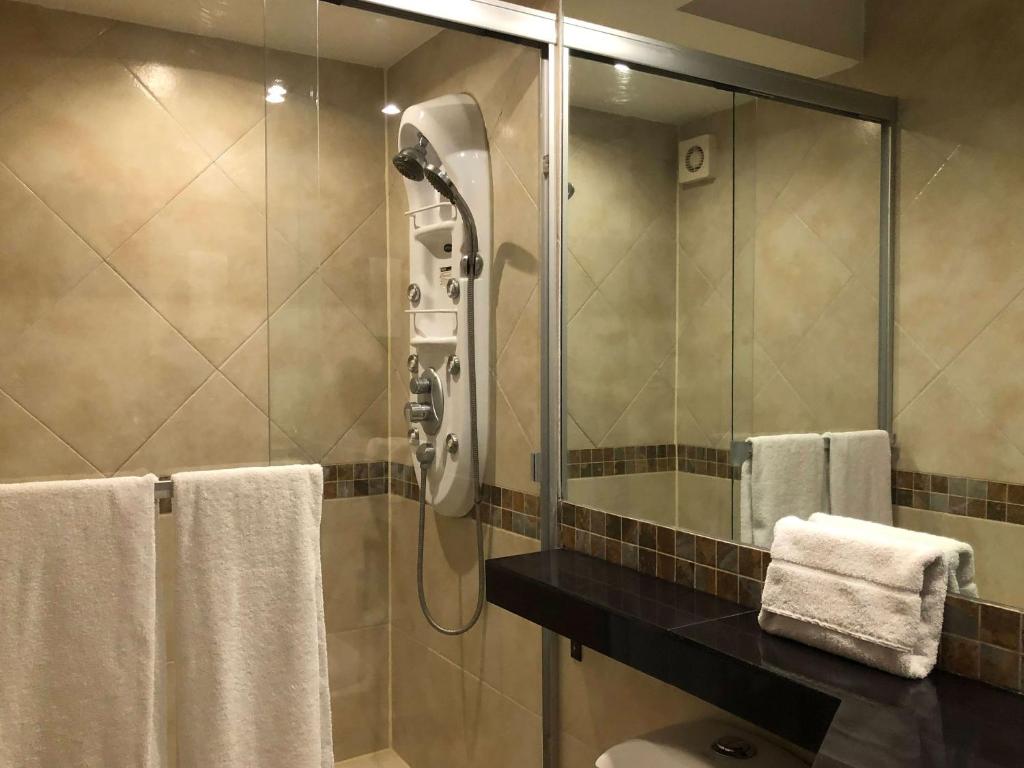 A tiled bathroom with a glass-enclosed shower and multi-jet shower panel.