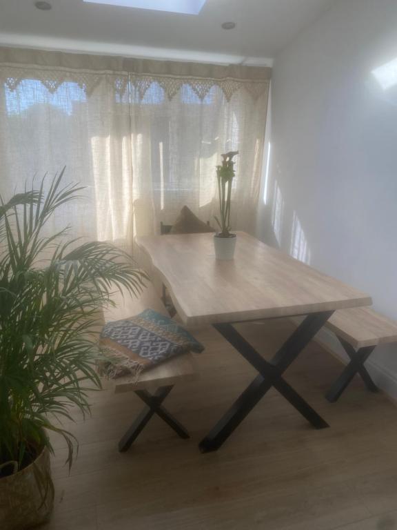 a wooden table and bench in a room with curtains at Avalon cottage in Glastonbury