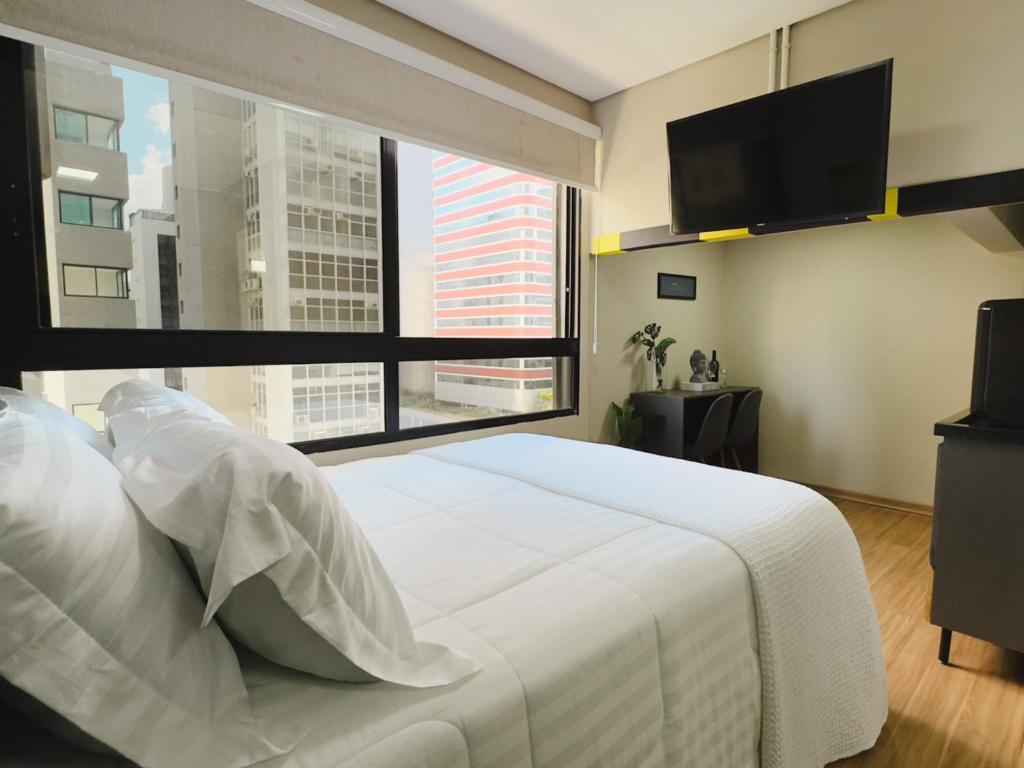 a bedroom with a large white bed and a large window at Apê Paulista Augusta in São Paulo