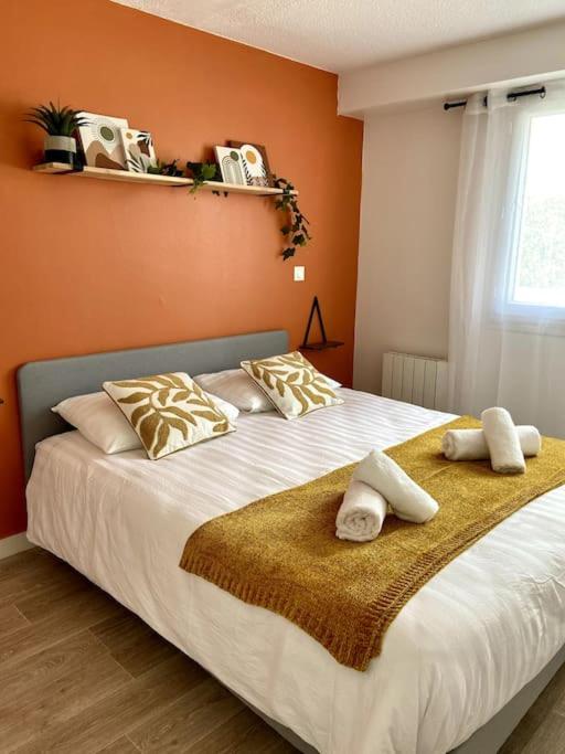 une chambre avec un grand lit avec des oreillers dessus dans l'établissement Le TerraBreizh, T2 cosy et confort avec parking privé, balcon et fibre, à Lorient