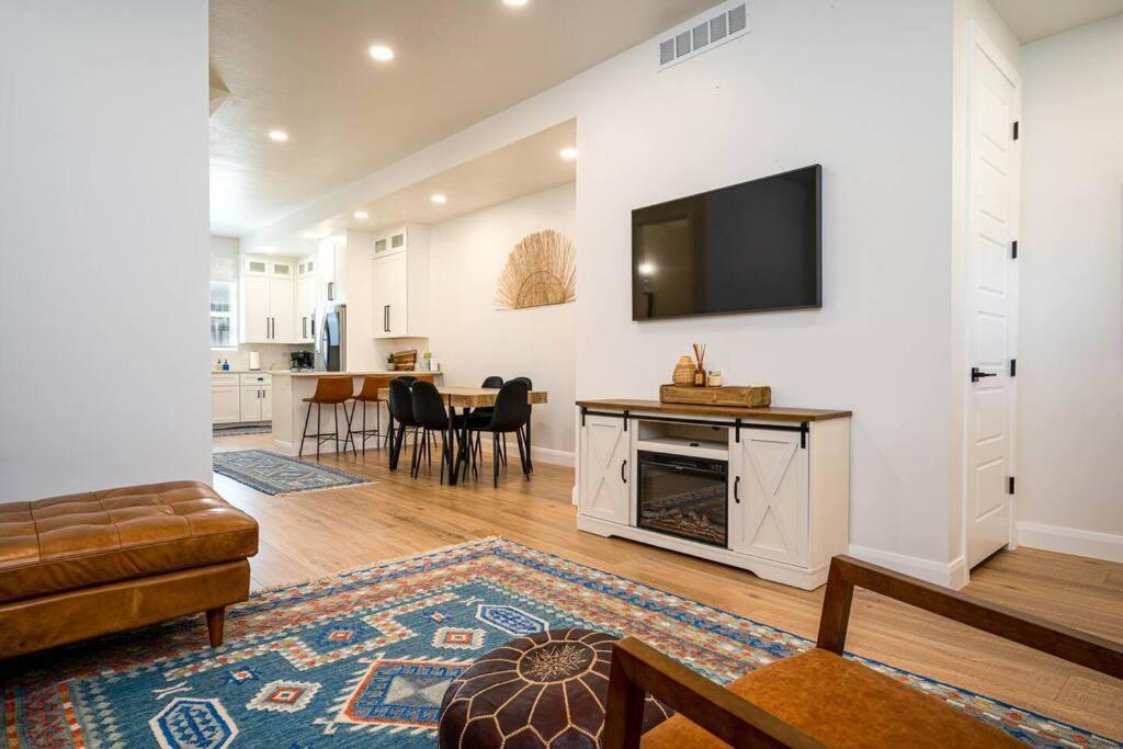 a living room with a television on a wall with a fireplace at Villages Alpine Escape in Eden